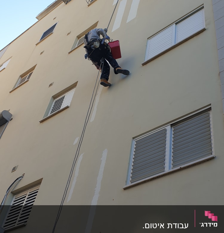 אדם על חבל אוטם קירות חיצוניים בבניין